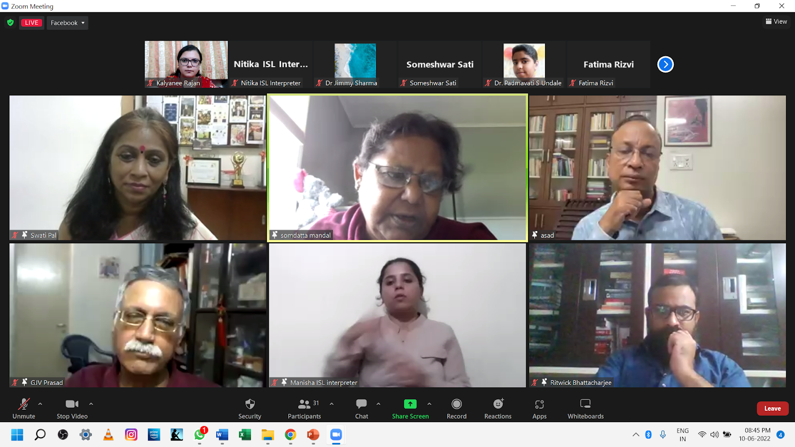 A Zoom meeting screenshot showing multiple participants in individual video feeds, with one person in the bottom center acting as an ISL interpreter.
