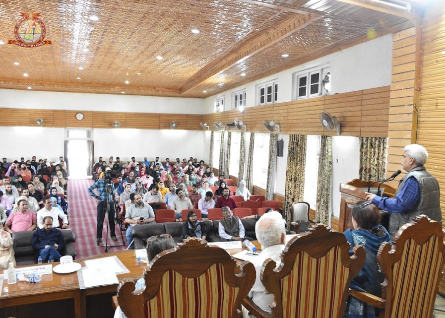 Audience listens attentively as professor someshwar sati addresses a full hall during the Two-day Workshop on Disability Studies at the University of Kashmir, with panelists seated on stage facing attendees.