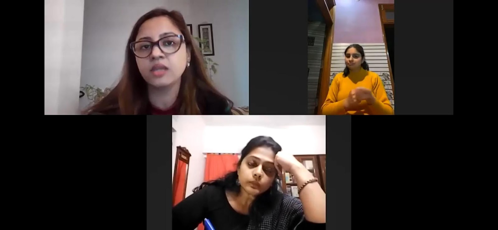 A screenshot from a video conference shows three women in separate frames: one speaking with glasses, another actively signing, and a third resting her head on her hand.